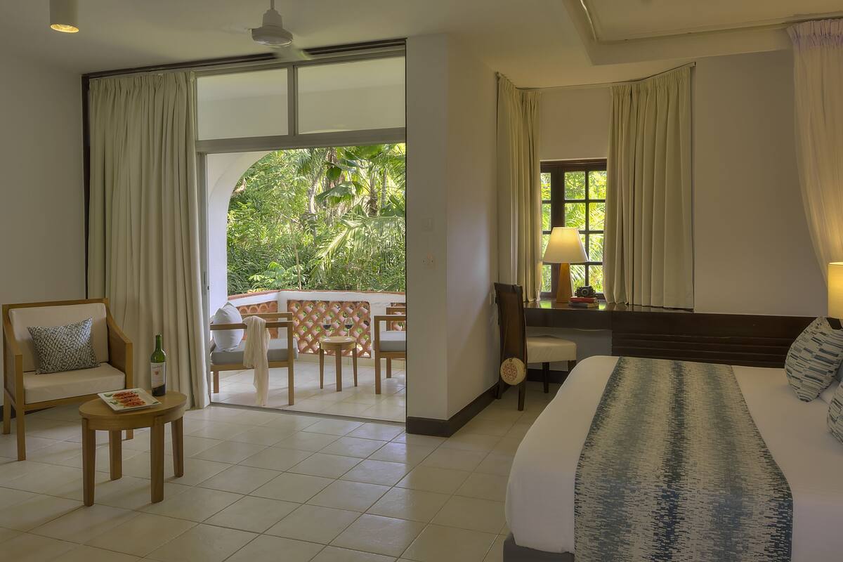 Une chambre d’hôtel avec un lit, une chaise, une petite table et une vue sur la verdure.