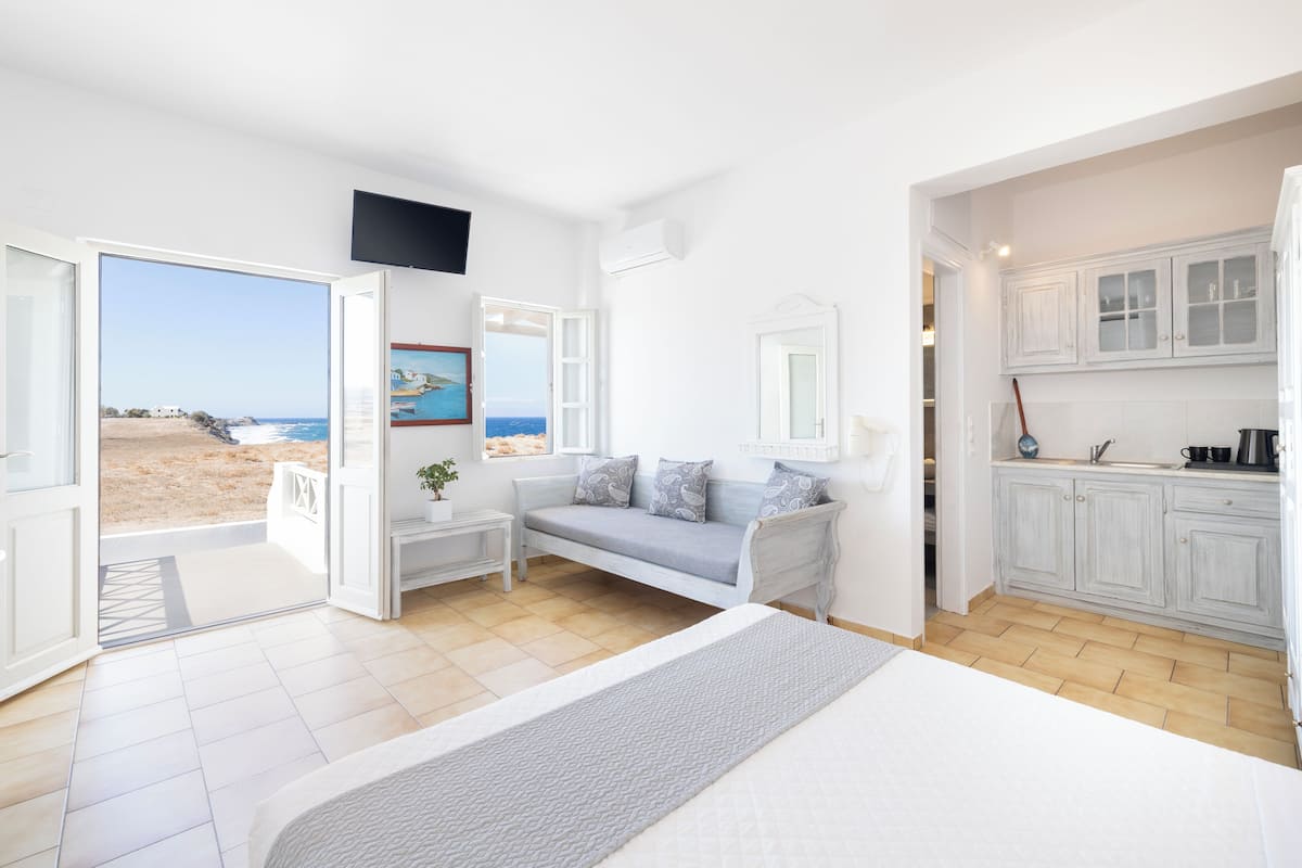 A bedroom with a bed, a sofa, and a view of the beach.
