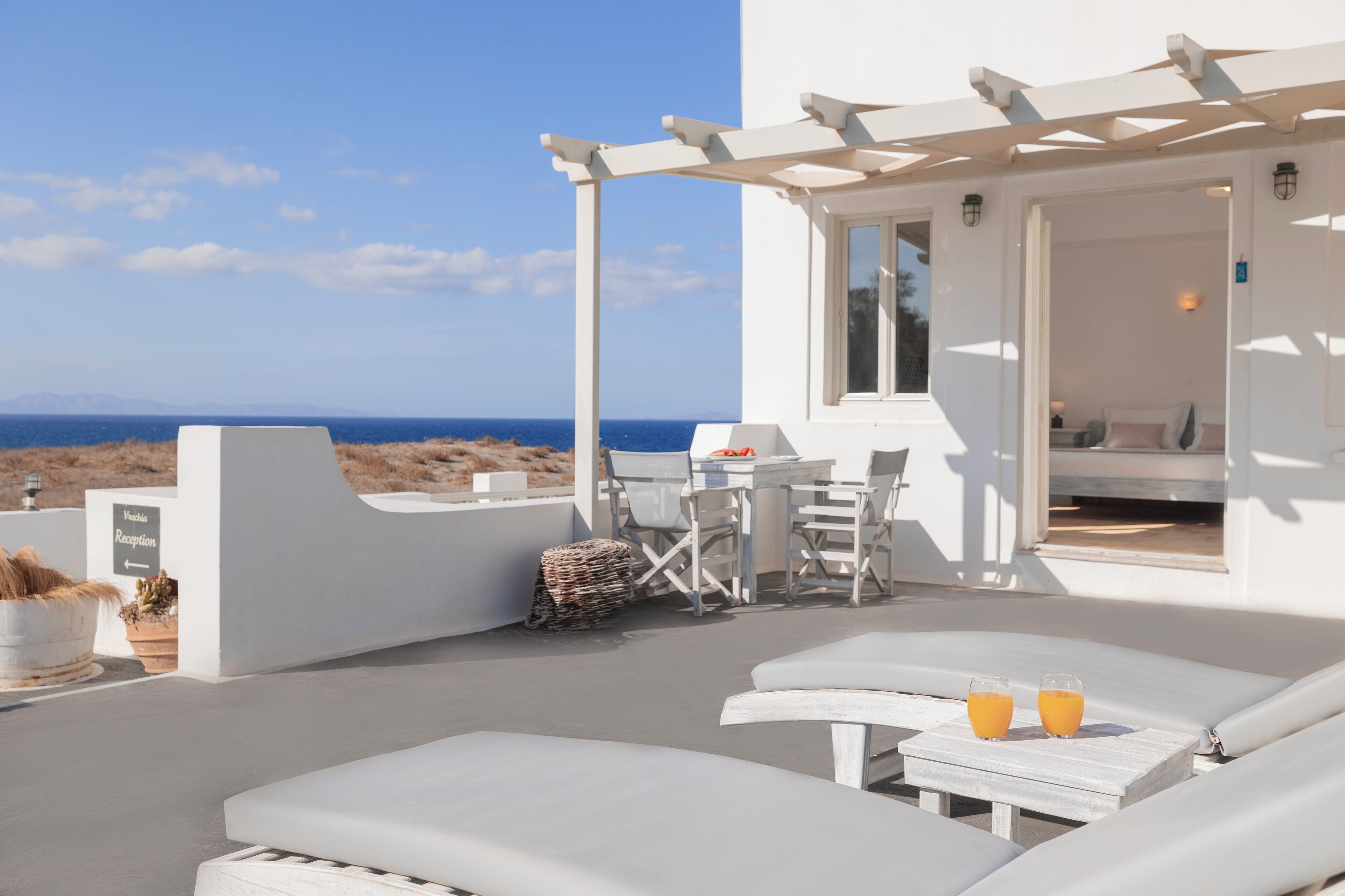 Zona relax esterna con sedie a sdraio e tavolo, con vista sul mare.