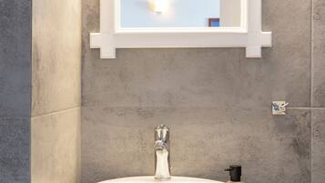 A bathroom with a white sink, a mirror, and a soap dispenser.