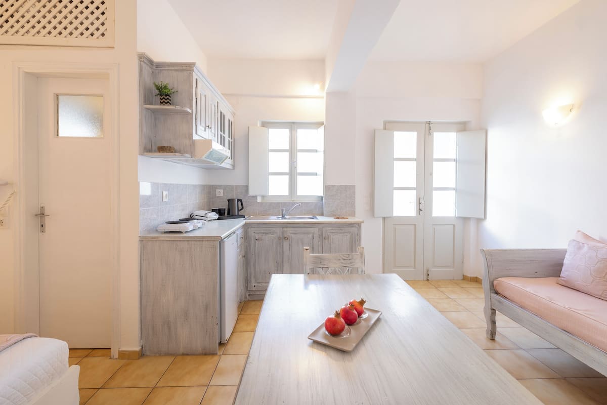 A modern kitchen with white cabinets, a central island, and a dining area with a table and a sofa.