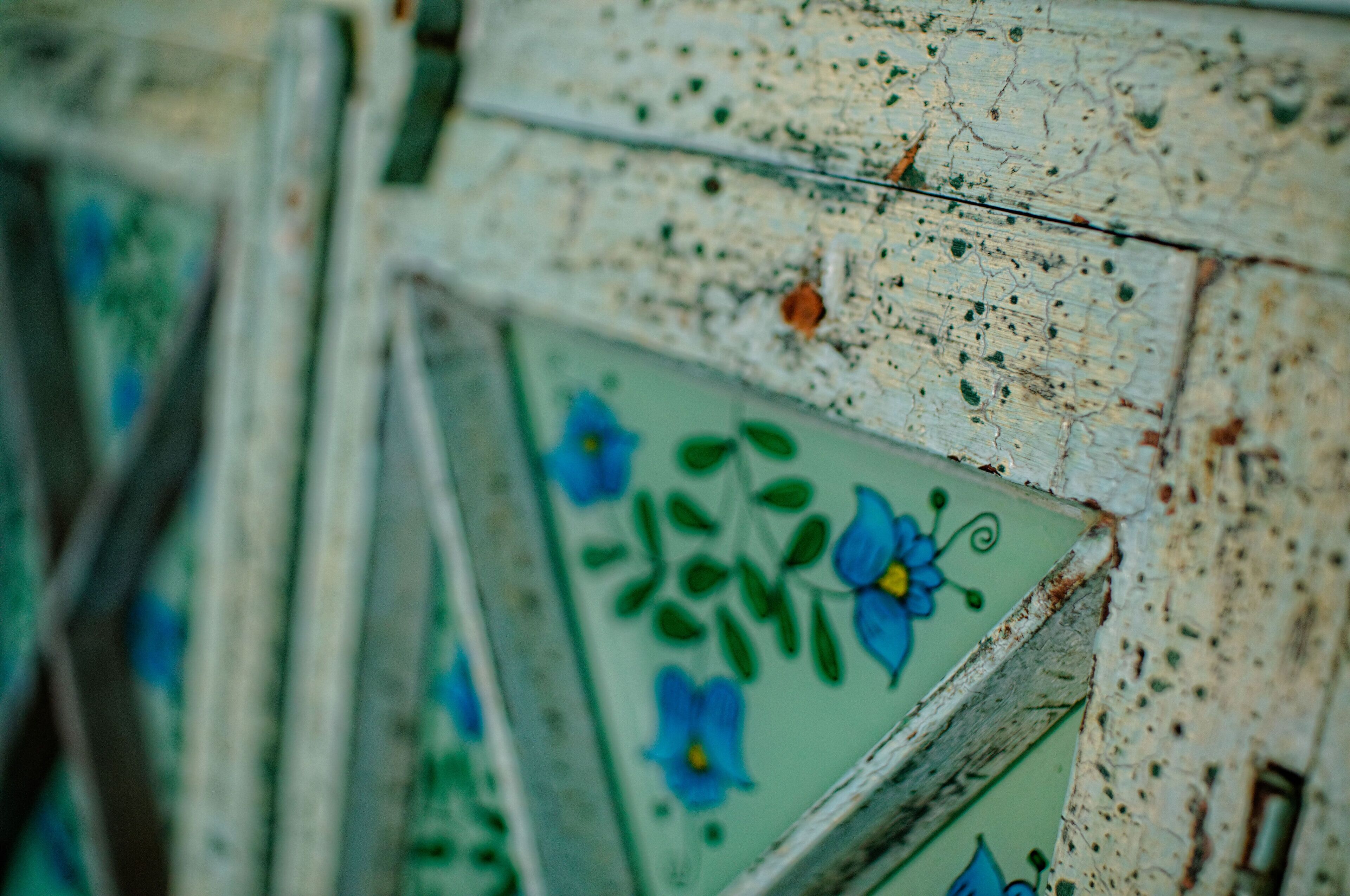 A close-up of a weathered wall with decorative tiles featuring blue flowers.
