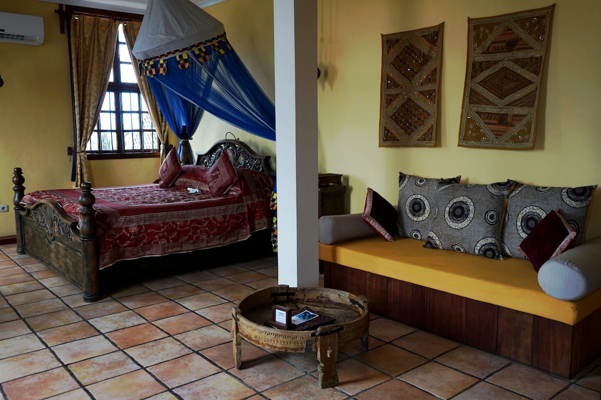 Una habitación con cama, sofá, una pequeña mesa redonda y decoración en la pared.
