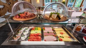 A buffet with various food items and a glass display case. - Almfrieden (Ramsau am Dachstein)