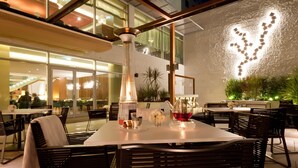 An outdoor dining area with tables and chairs, a decorative light fixture, and a wall with a light projection.