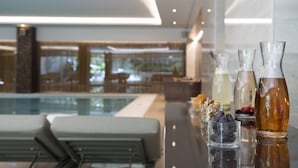 A modern hotel lobby with a pool, seating area, and a bar with various beverages and snacks.