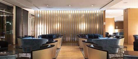 A modern lobby with a central seating area, a wooden floor, and a vertical panel wall.
