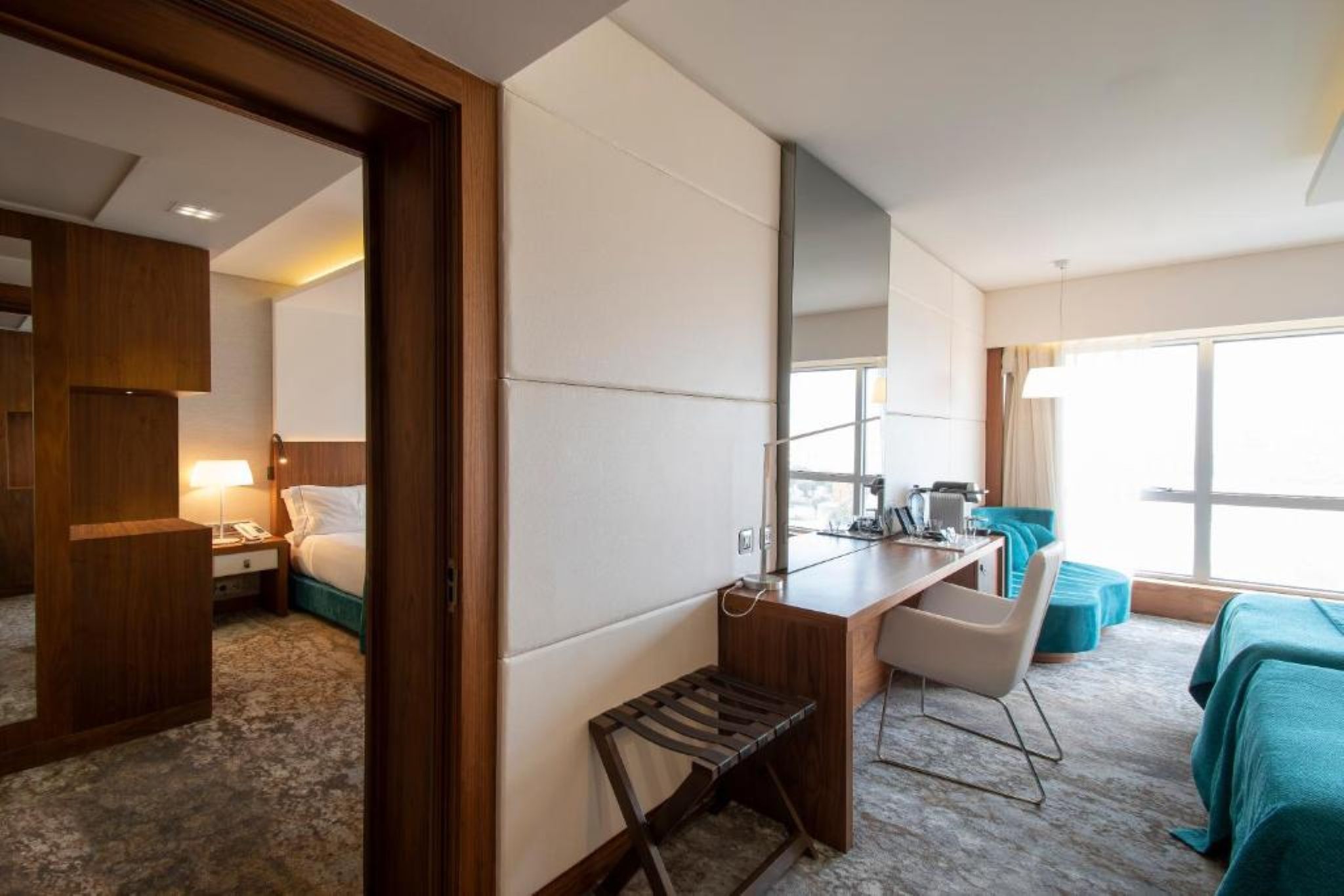Habitación de hotel con cama, escritorio, silla y vistas al exterior.