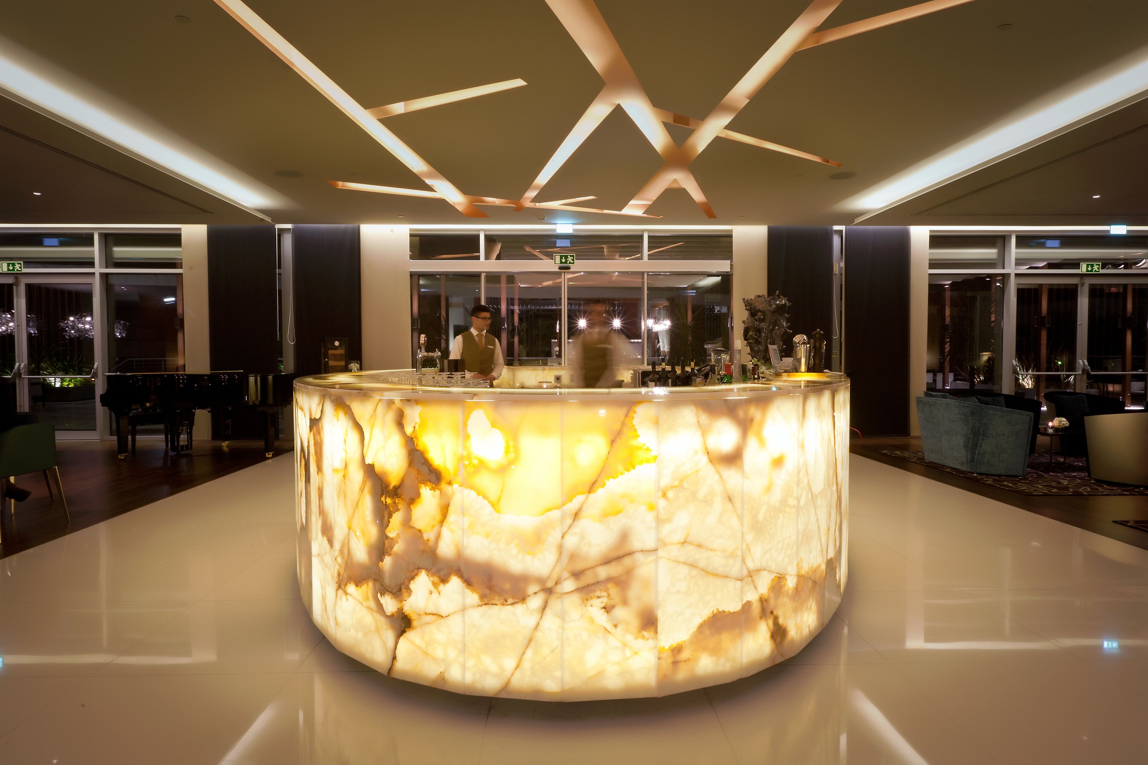 Un elegante mostrador de recepción de mármol en un moderno vestíbulo de hotel, con piso pulido y luminarias contemporáneas.