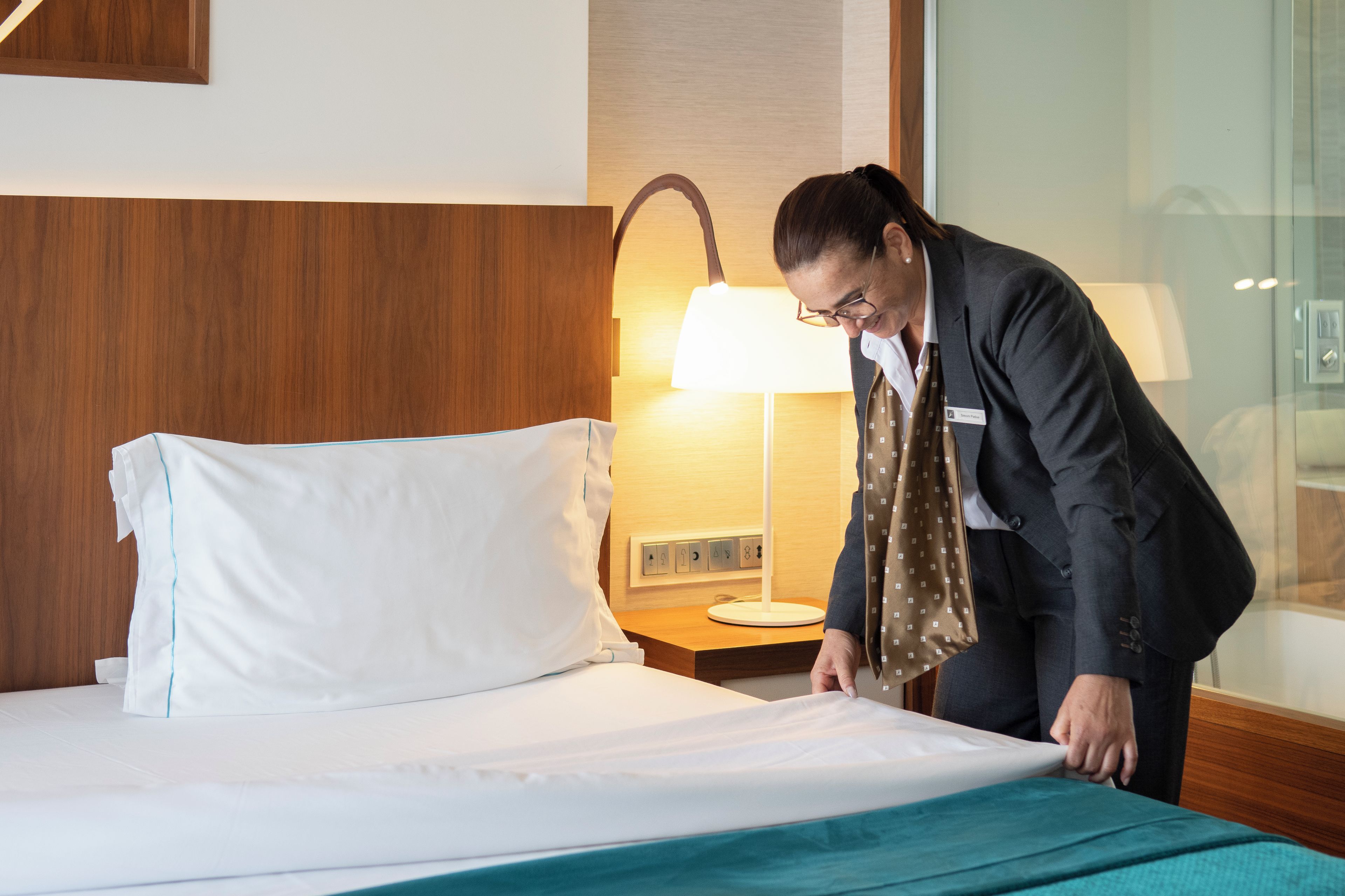 Una habitación de hotel con una cama, una mesita de noche y una lámpara.