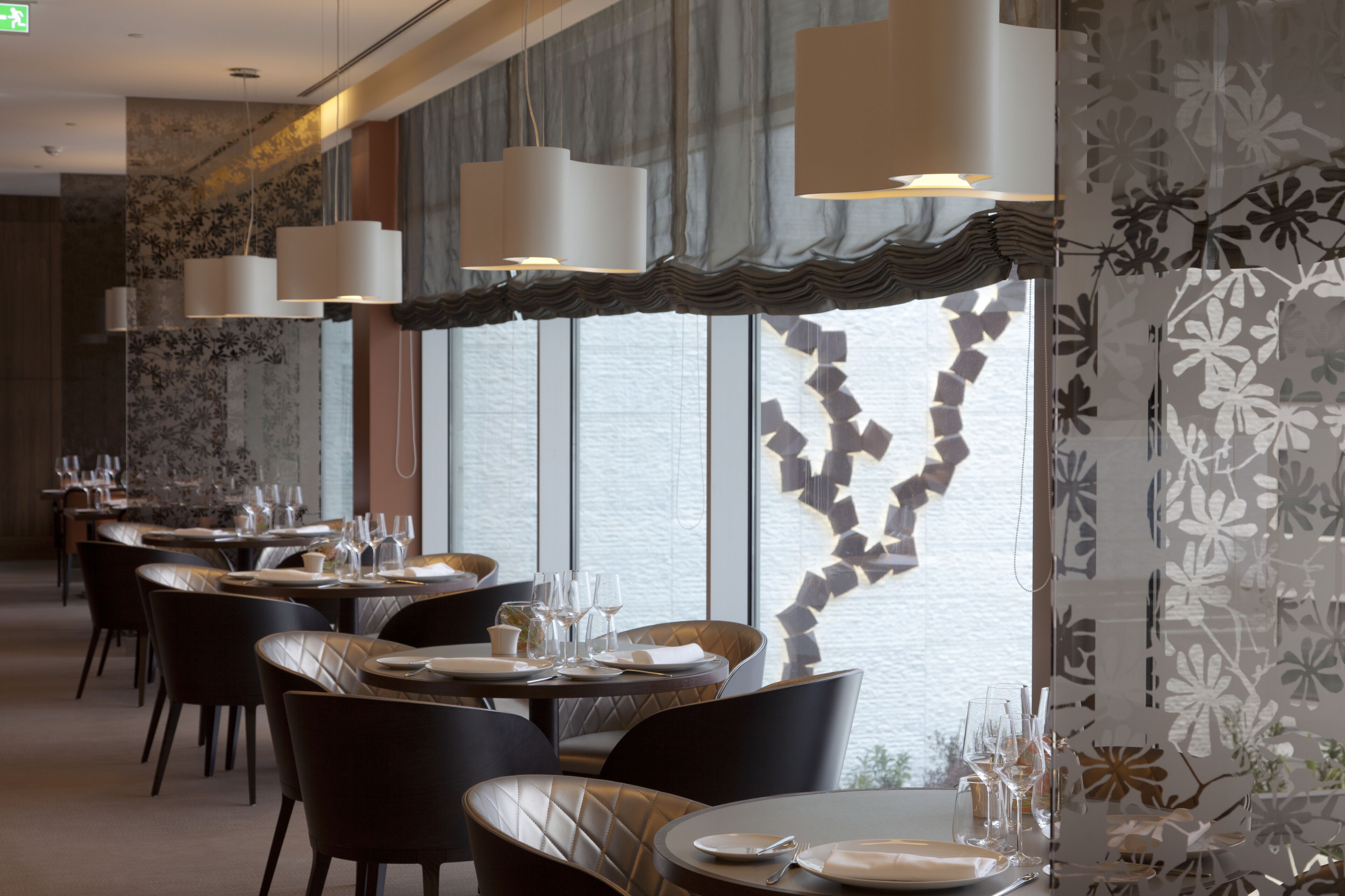 Un ristorante con diversi tavoli, sedie e lampadari pendenti.