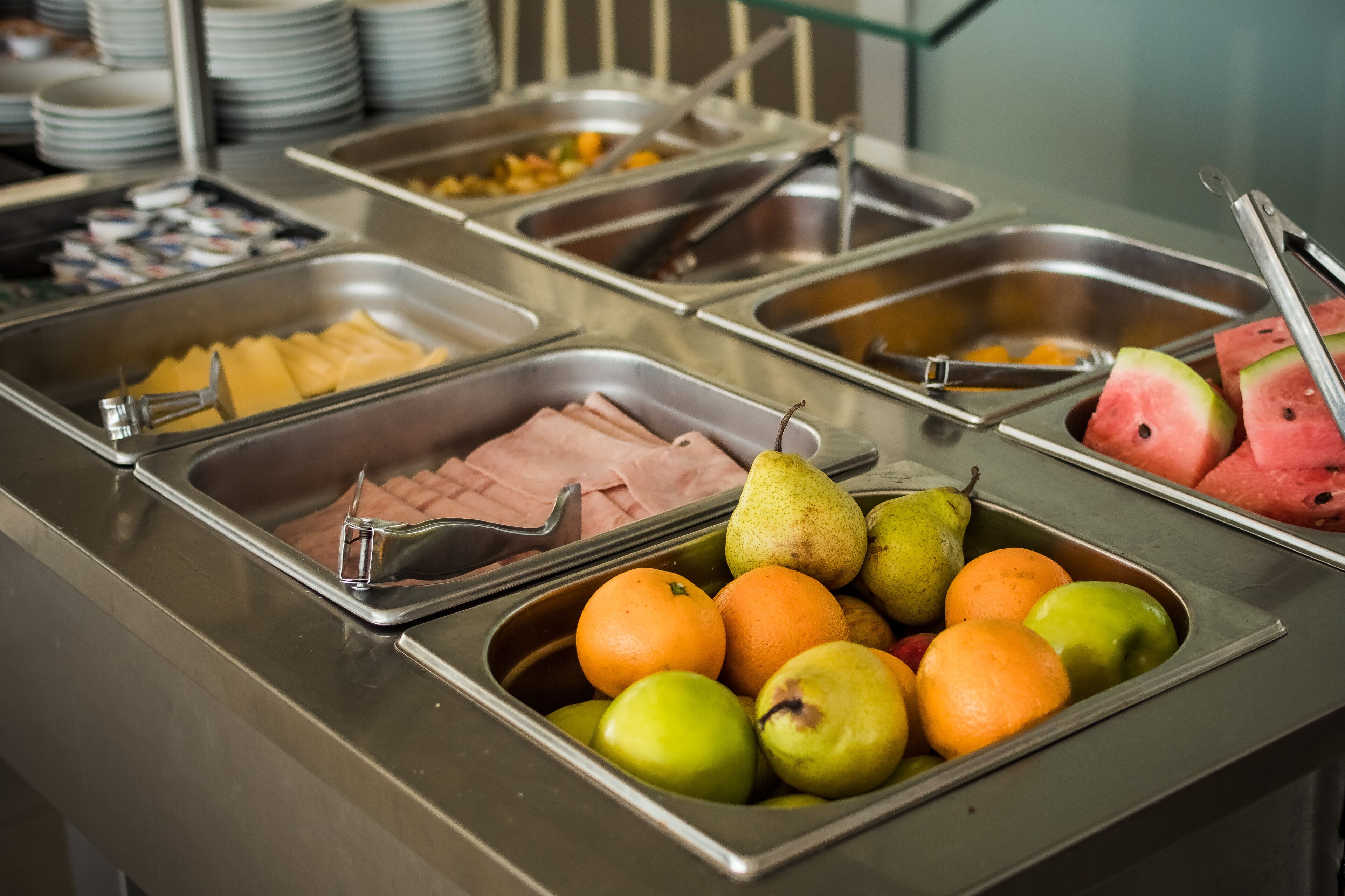Un buffet proposant une variété de plats, notamment des fruits, des légumes et des viandes.