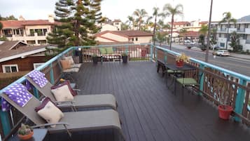 Um deck de madeira com cadeiras de descanso e uma mesa, cercado por um corrimão.