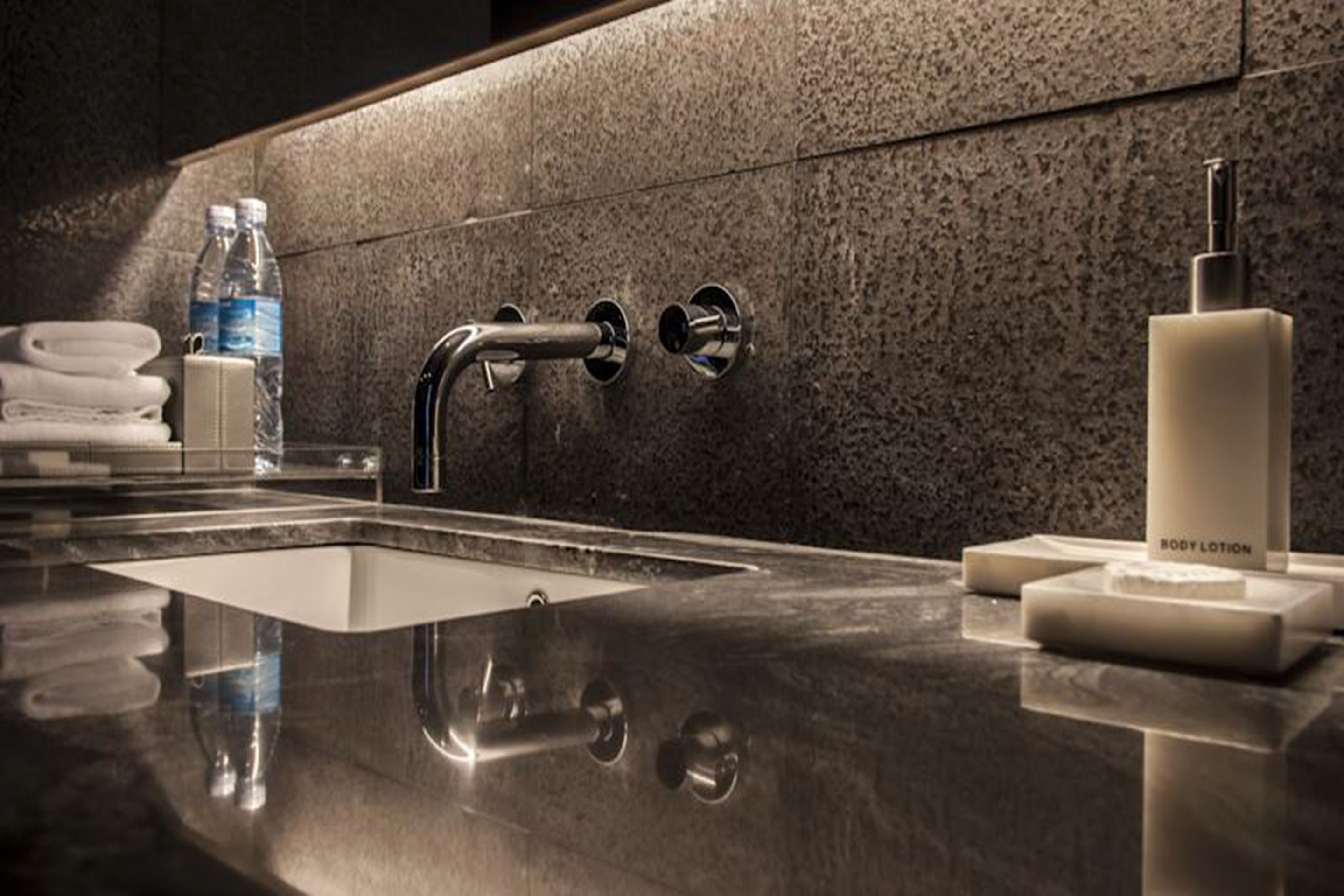 A modern bathroom with a stainless steel sink, a towel dispenser, and a soap dispenser.
