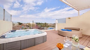 A rooftop terrace with a hot tub, seating area, and a table with drinks and flowers. - Zafiro Ca'n Picafort (Santa Margalida)