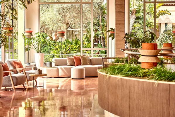 Uma sala de estar moderna com um sofá, uma mesa de centro e uma grande janela com vista para um jardim exuberante.