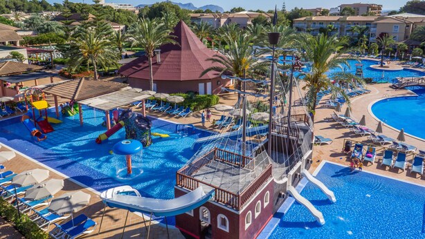 A large swimming pool with a pirate ship play area, palm trees, and lounge chairs. - Zafiro Ca'n Picafort (Santa Margalida)