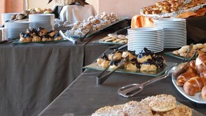 A buffet table with various pastries and desserts, including croissants and other baked goods.