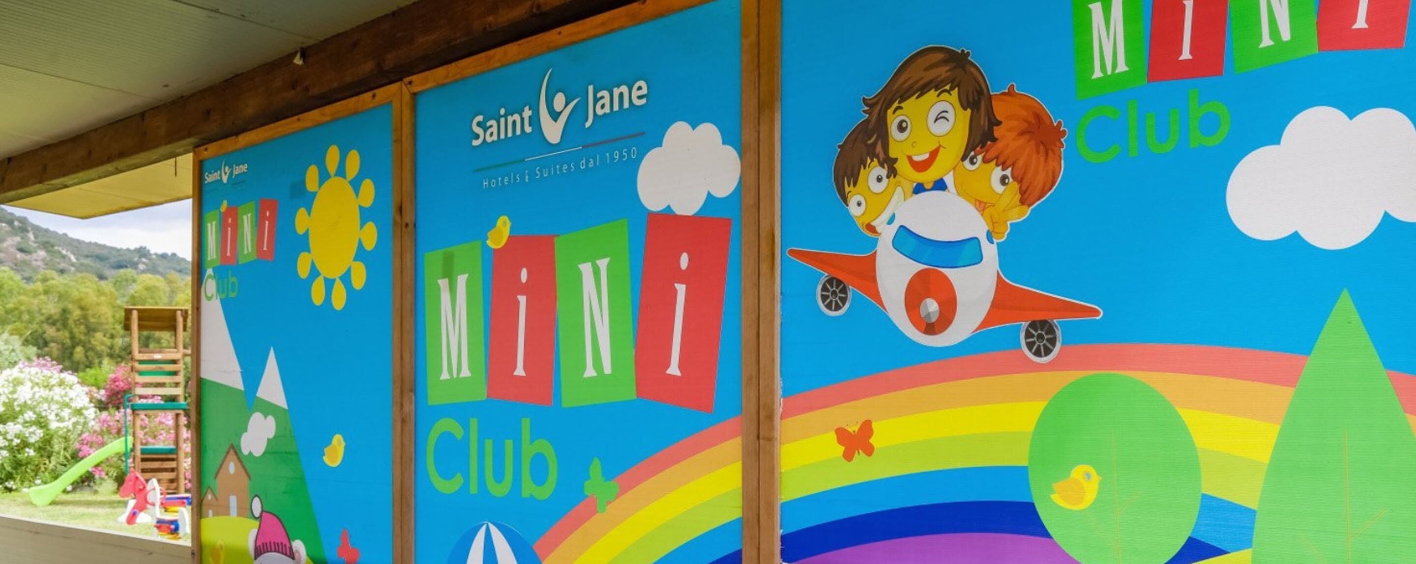 Um mural colorido para o Saint Jane Mini Club, com sol, nuvens, um arco-íris e um foguete.