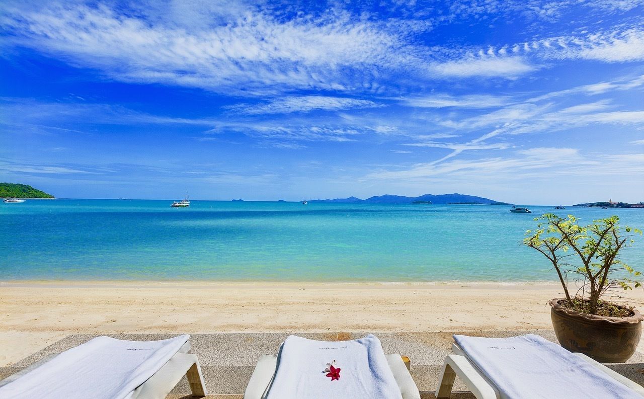 Di pantai, pasir putih, dan kursi berjemur