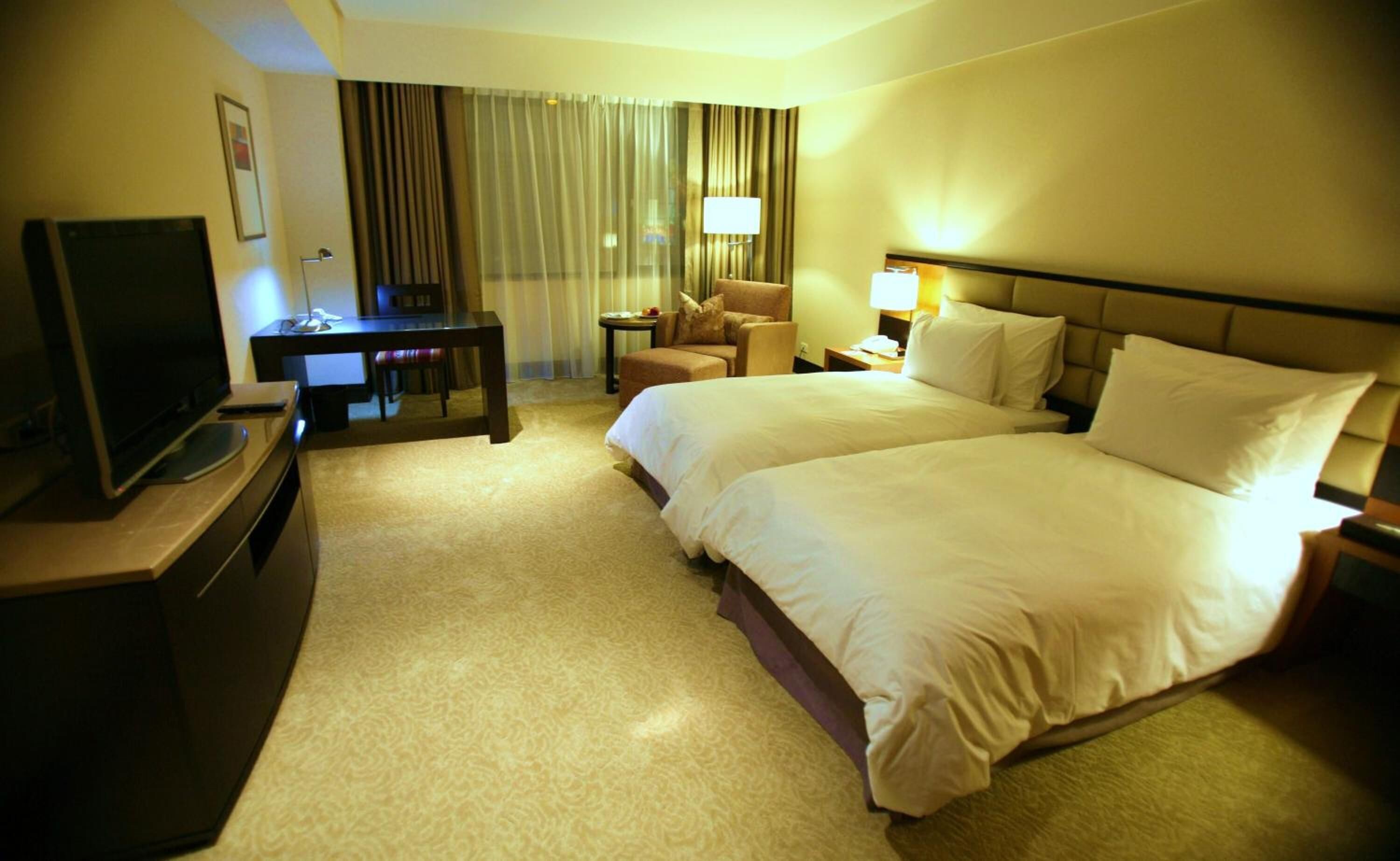 A hotel room with a bed, a desk, a television, and a chair.