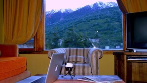 Ein Zimmer mit einem Laptop auf dem Tisch, einem gestreiften Sessel und einem Fernseher.