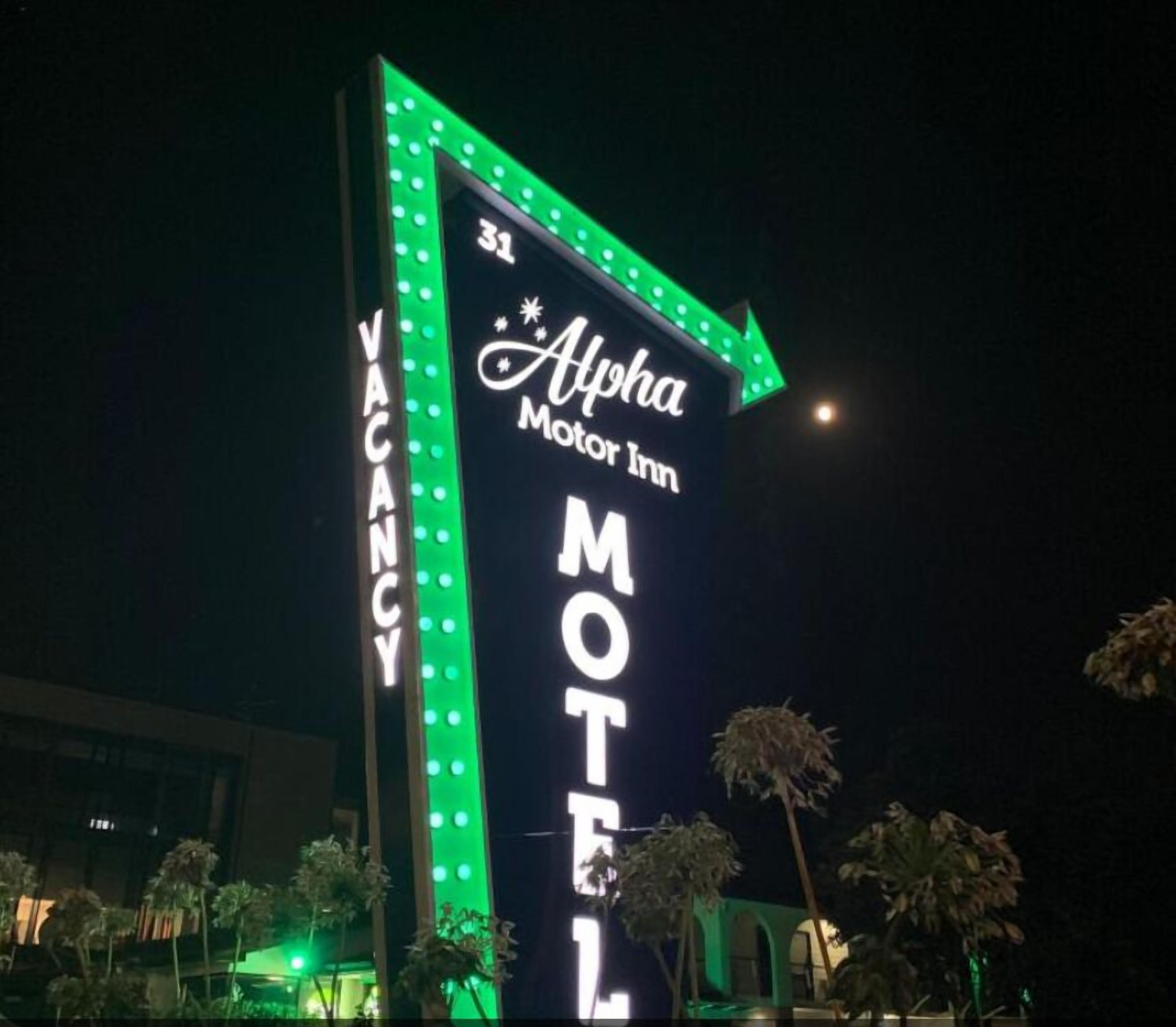 A neon sign for the Alpha Motor Inn Motel with a vacancy indicator.