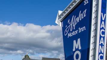 A blue sign for Alpha Motor Inn with a 'VACANCY' label.
