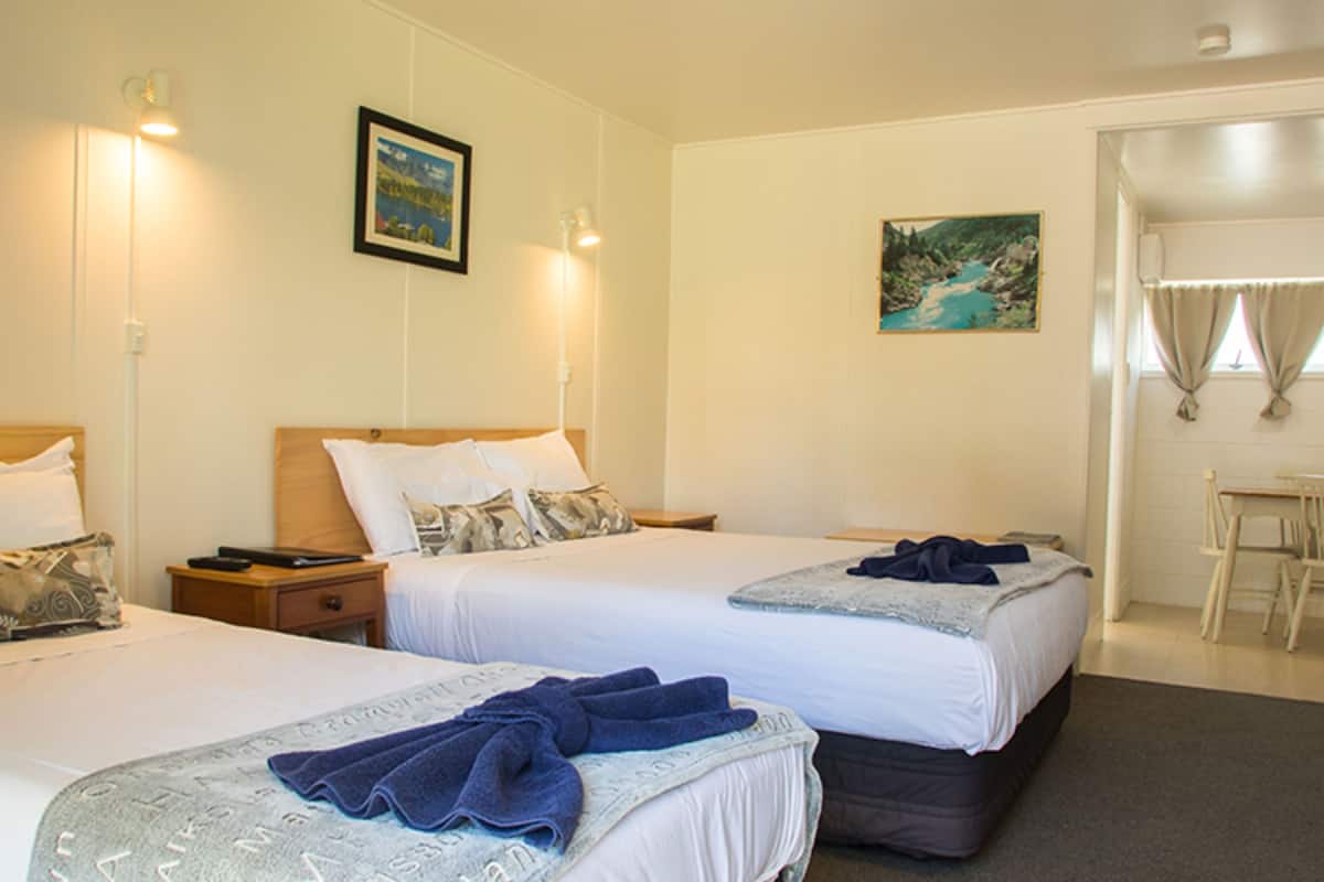Quarto de hotel com duas camas, uma escrivaninha e uma cadeira.