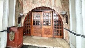Une porte en bois en arc de cercle, dotée de panneaux de verre, et un mur en marbre.