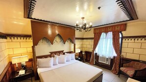 Une chambre d’hôtel avec un grand lit, une table de chevet avec une lampe, un canapé et une fenêtre avec des rideaux.
