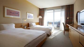 Ein Hotelzimmer mit zwei Betten, einem Schreibtisch, einem Fernseher und einem Balkon mit Blick.