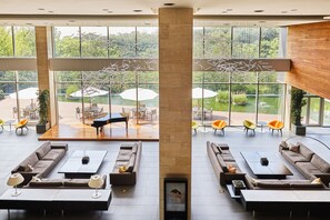 Amplio espacio interior con diversas opciones de asientos, grandes ventanales que ofrecen vistas a un jardín y una zona de estar al aire libre.