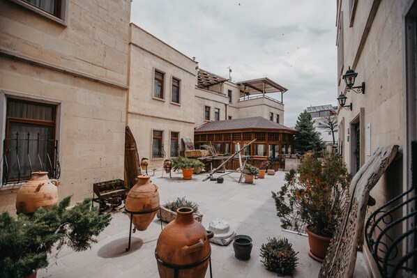 Un patio con macetas de terracota, un banco de madera y plantas en macetas.