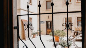 A view through a window with a metal railing, featuring a building with multiple windows and a door labeled "BUREAU." - Royal Stone Houses - Goreme (Nevsehir)