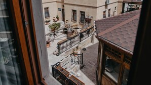 A view from a window overlooking a courtyard with buildings, a wooden balcony, and a tiled roof. - Royal Stone Houses - Goreme (Nevsehir)