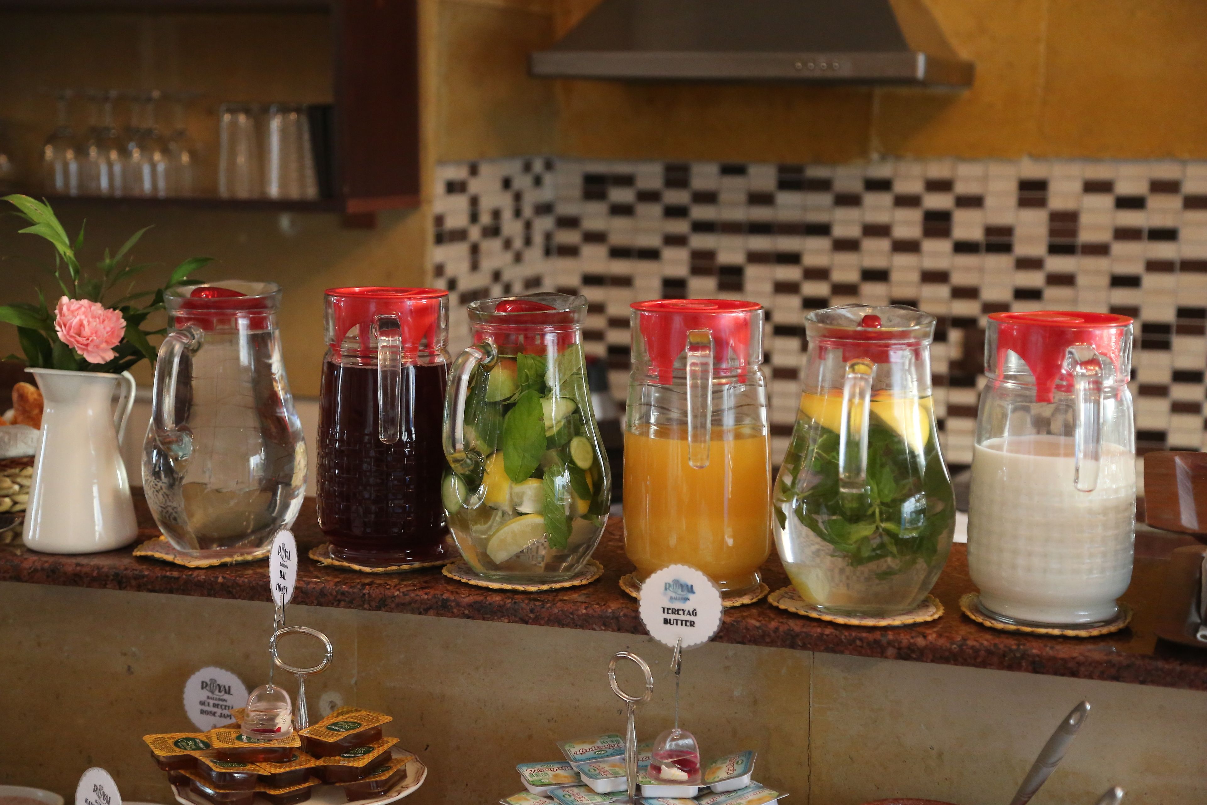 A kitchen counter with various food and drink items, including jars of condiments and a pitcher of milk.