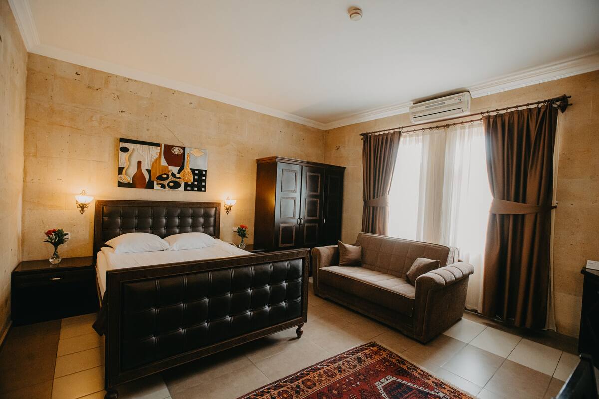 Een slaapkamer met een bed, een bank, een kast en een vloerkleed.