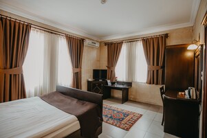 Habitación de hotel con cama, escritorio y televisión.