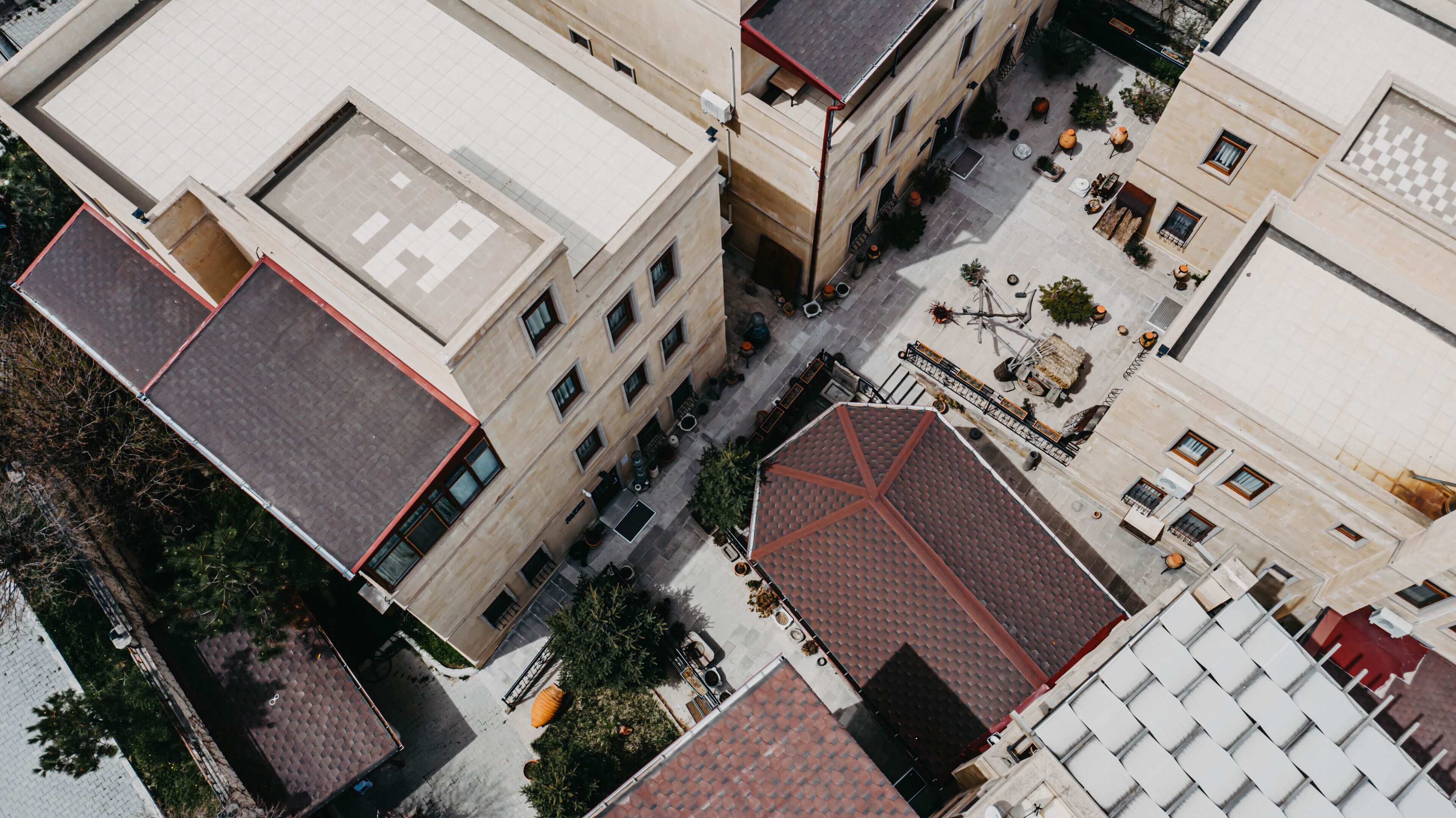 Vista aérea de um complexo de edifícios com vários andares, varandas e um pátio com mesas ao ar livre.