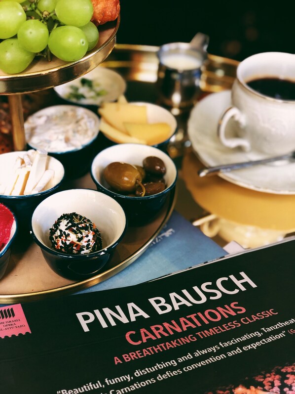 A book titled "Pina Bausch: Carnations" with a tray of food items including grapes, cheese, and olives. - The Rothschild Hotel Tel Aviv's Finest (Tel Aviv)