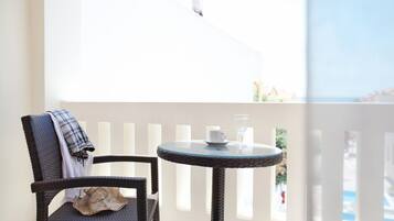 Una silla de mimbre con una manta escocesa y una mesa de vidrio con una taza y un vaso.