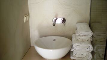 A bathroom with a white sink, a towel rack with folded towels, and a shower area.