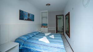 Un dormitorio con cama, escritorio, silla y un cuadro en la pared.
