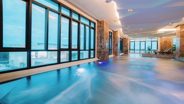 A spacious indoor swimming pool with large windows and a view of the cityscape. - Lumen Bangkok Srinakarin (Bangkok)