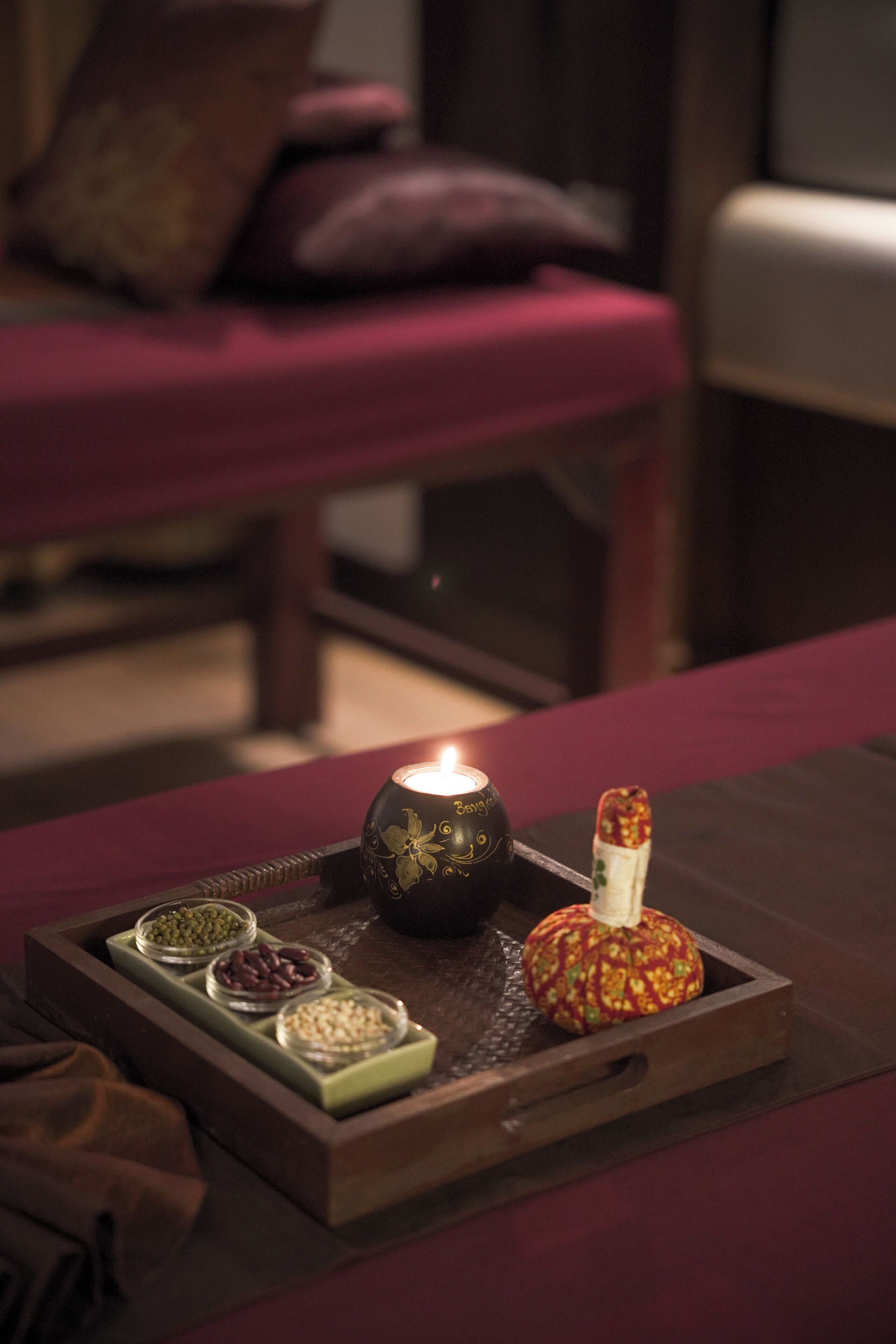 A tray with a candle, a decorative pumpkin, and small bowls of spices on a table.