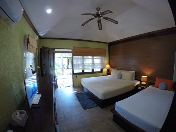 A hotel room with two beds, a ceiling fan, a TV, and a window with a view of the outdoors. - O.P. Bungalow (Koh Samui)