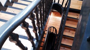 Un escalier en bois avec une rampe en métal noir.