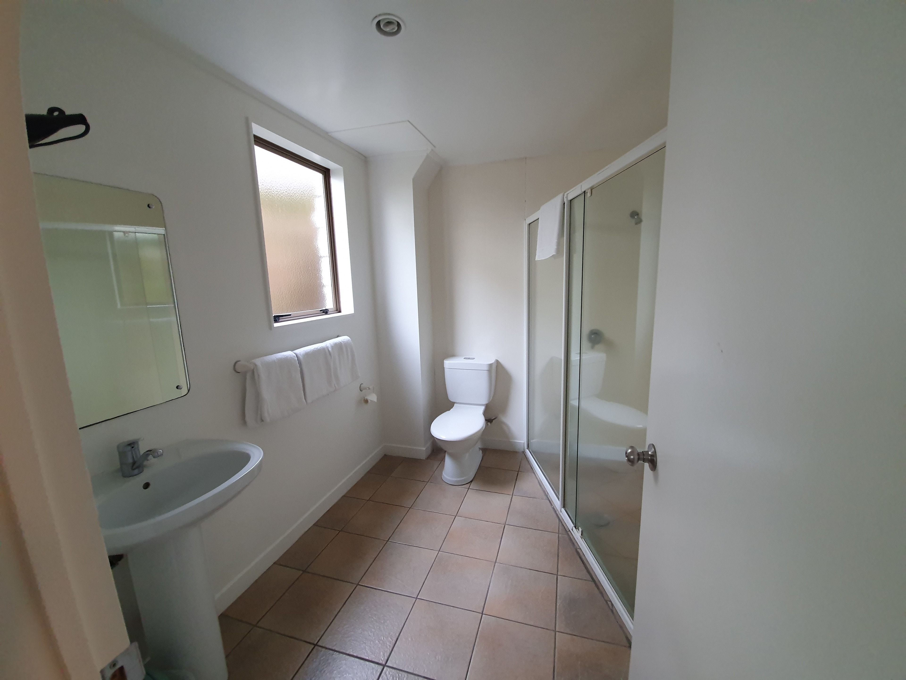 Een badkamer met een wastafel, toilet en een douchecabine met glazen wanden.