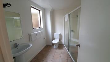 Een badkamer met een wastafel, toilet en een douchecabine met glazen wanden.